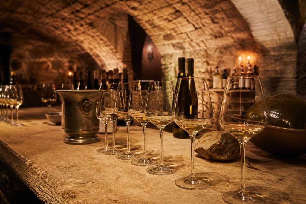 Séance de dégustation dans une cave alsacienne avec verres de vin blanc alignés sur table de pierre
