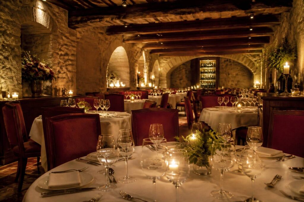 Salle de restaurant gastronomique élégante avec tables nappées, pierres apparentes et bougies