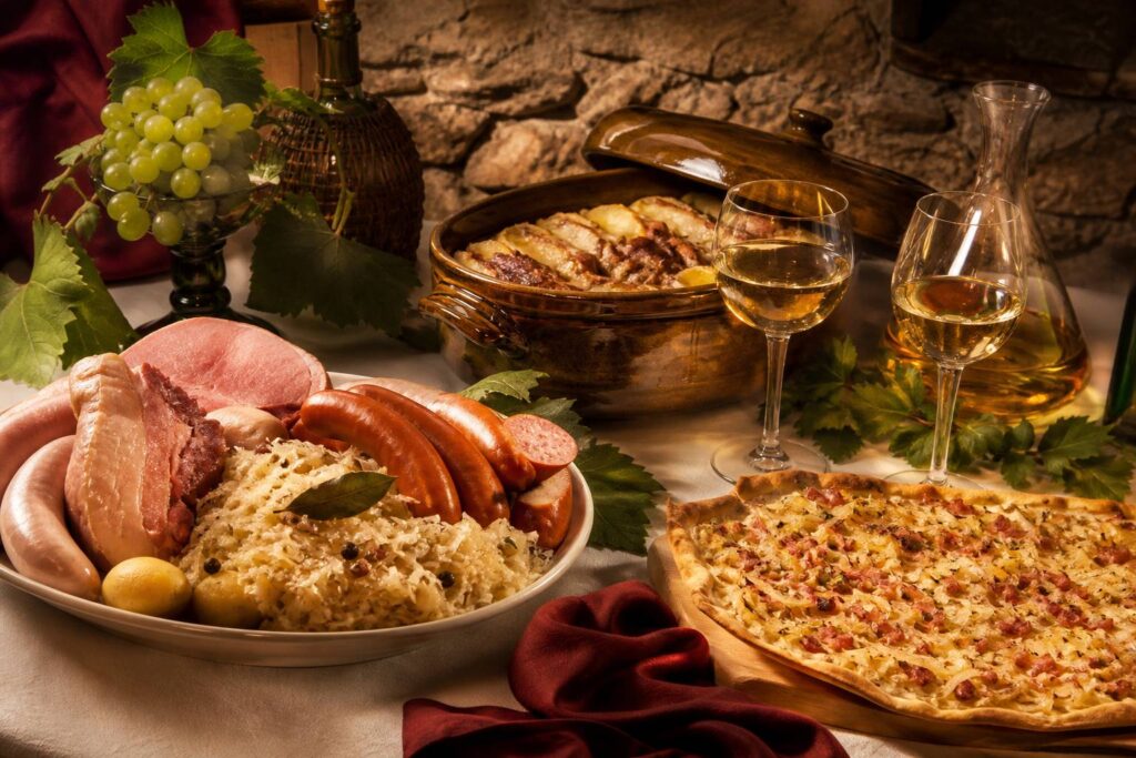 Table de spécialités alsaciennes avec choucroute garnie, tarte flambée et baeckeoffe en terrine