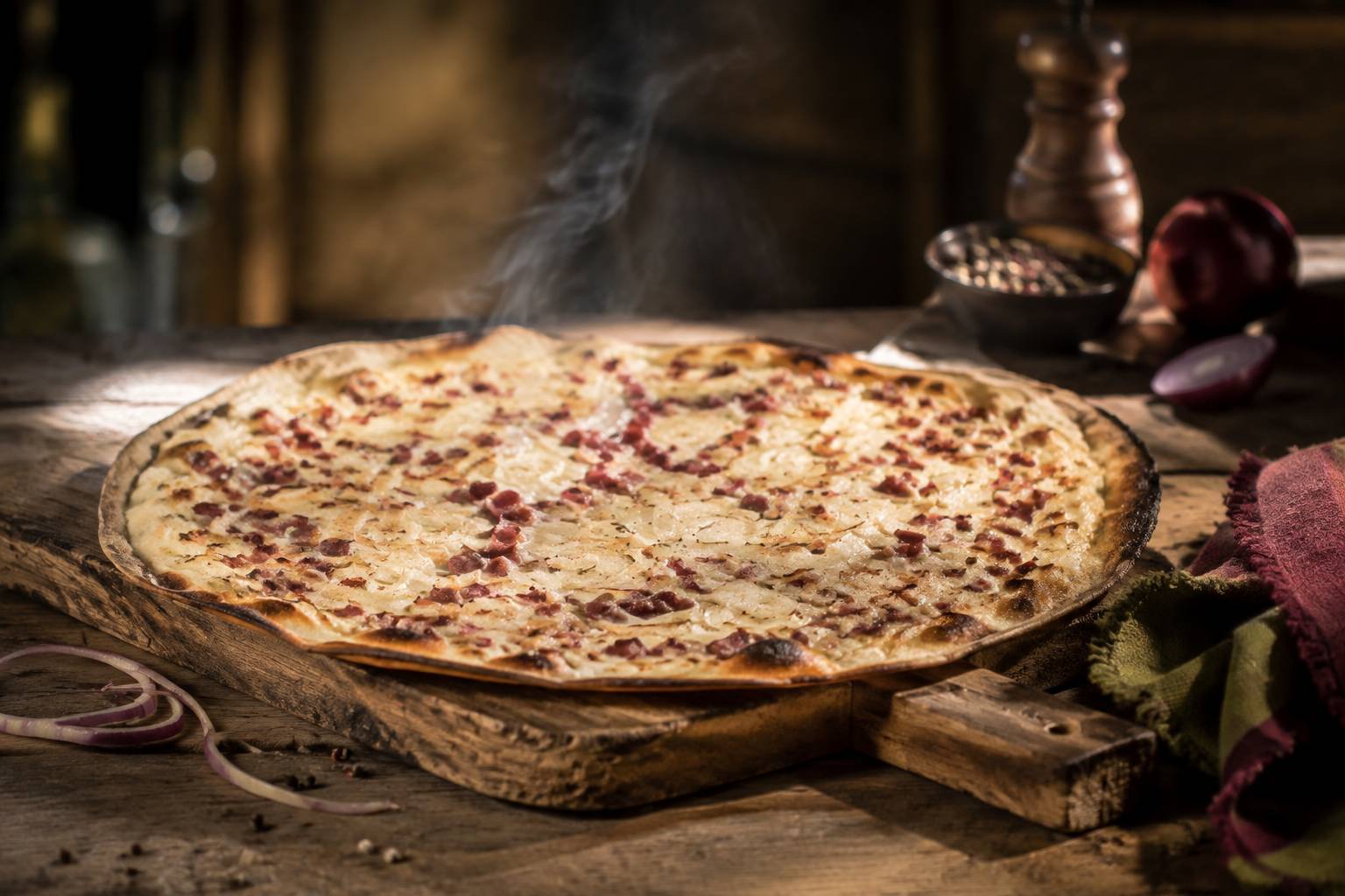 Tarte flambée croustillante aux lardons et oignons sur une planche en bois, fine vapeur